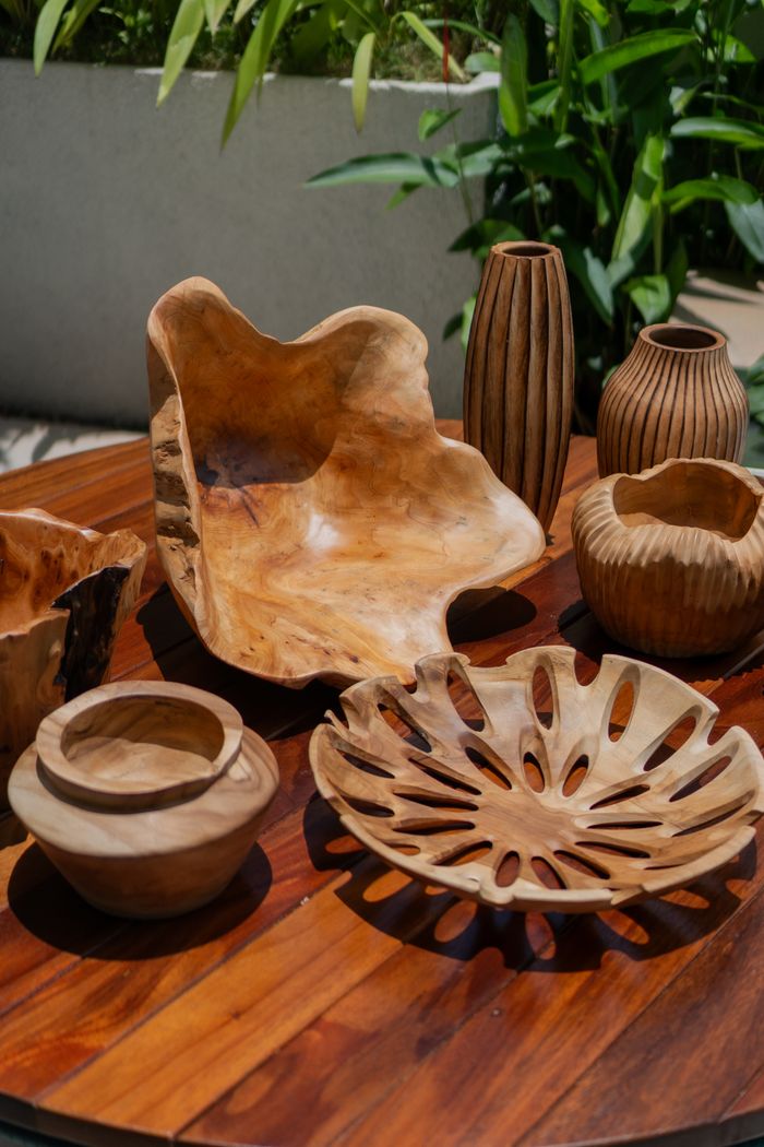 services-04 Artistic wooden bowls and vases arranged on a table outdoors, showcasing craftsmanship.