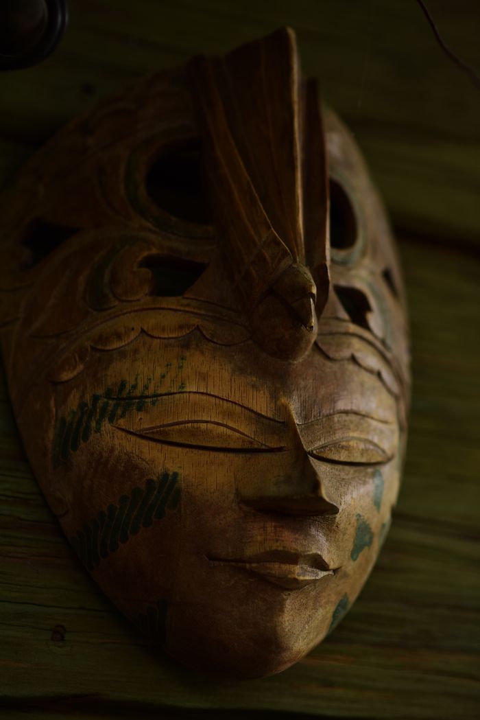 The Art of Drawing Readers In: Your attractive post title goes here A detailed tribal wooden mask with green accents displayed on a rustic wooden wall.