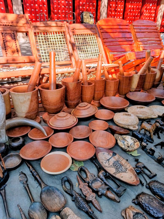 A vibrant collection of handcrafted wooden kitchen utensils and art pieces on display outdoors.